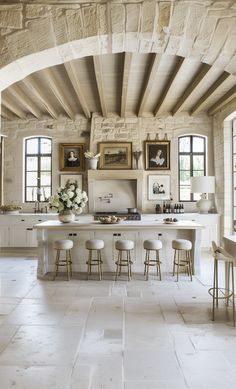 a kitchen with an archway leading to the dining room and living area, along with white countertops and stools