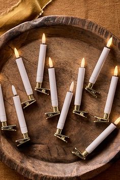 white candles are arranged in a circle on a wooden platter with gold trimmings