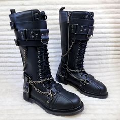 Bolt-415 By Demonia Vegan Leather 1 1/4" Heel Size: Men's 1.25" (32mm) Heel 18 Eyelet Unisex Knee High Combat Boot Featuring Featuring Studded Buckled Top Panel, Harness Strap, O-Ring, D-Ring , Hanging Chain Details And Branded Metal Plate @ Toe, Inside Zip Closure. Silver Punk Boots For Streetwear, Silver Gothic Boots With Metal Feet, Gothic Silver Boots With Metal Feet, Leather Boots With Protective Metal Feet For Concerts, Gothic Silver Boots With Round Toe, Silver Boots With Rivets And Round Toe, Silver Round Toe Boots With Rivets, Silver Leather Moto Boots With Round Toe, Emo Fashion Men