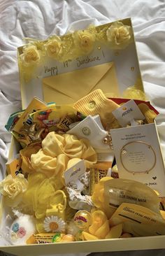 a yellow box filled with lots of different types of items on a white sheet covered bed