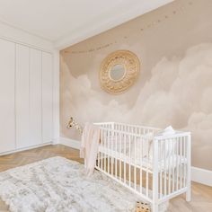 a baby's room with a white crib in the middle and a wall mural behind it