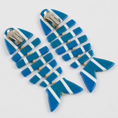 four blue and white fish shaped clips on a white surface with one clip in the shape of an arrow