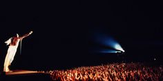 a man standing on top of a stage with his arms up in front of him