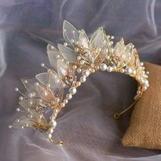 a tiara with pearls and leaves on top of a cloth bag next to a pillow