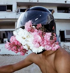 a man wearing a helmet with flowers on it's face and his hand out to the side