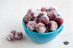 powdered sugar coated fruit in a blue bowl on a white table top next to it