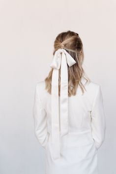 a woman in a white suit with a large bow on her head and back view