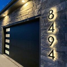 an image of a modern house with numbers on the wall and lights above the garage door