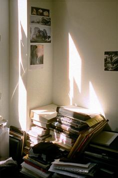 a stack of books sitting on top of a wooden floor next to a window filled with sunlight