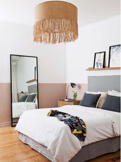 a bedroom with a bed, mirror and hanging lamp in the corner next to it