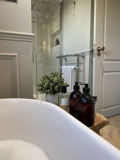 a white bath tub sitting next to a bathroom sink with two bottles on top of it