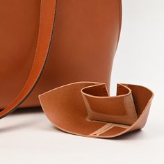 a brown leather bag and its strap are on the ground next to it's pouch