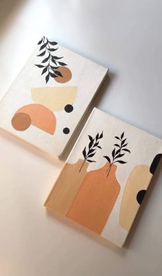 two canvases with abstract designs on them sitting on a table next to each other