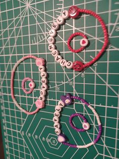 several different types of hair ties on a green board with white and pink letters that spell out hello kitty