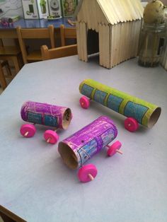 three rolls of toilet paper sitting on top of a table next to some pink rollers