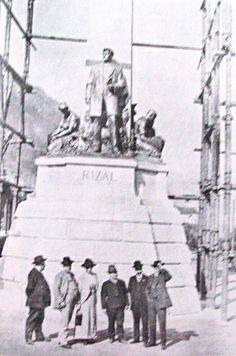 black and white photograph of men standing in front of a statue