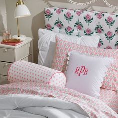 a bed with pink and white sheets, pillows and a pillow on top of it