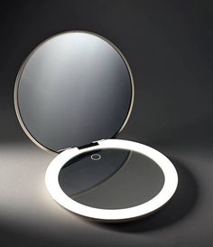 a round mirror sitting on top of a table next to a black wall and floor