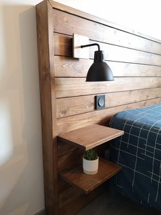 a bed with a wooden headboard and night stand next to the wall mounted lamp