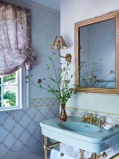 a bathroom with a sink, mirror and flowers in the vase on the counter top