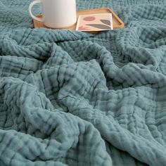 there is a cup on the bed with a blanket