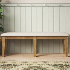 a wooden bench sitting on top of a rug next to a potted plant