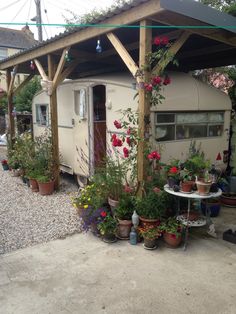 an old trailer is covered with flowers and potted plants