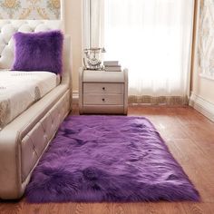 a bedroom with a bed, nightstand and purple rugs on the wooden flooring