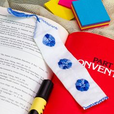 an open book with blue flowers on it next to a pen and marker, surrounded by other books