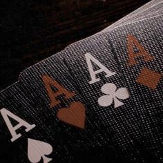 playing cards with ace symbols on them sitting on top of a wooden table in the dark