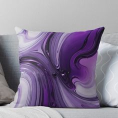 a purple and white pillow sitting on top of a couch next to a gray throw pillow