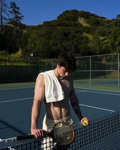 a shirtless man holding a tennis racket and ball