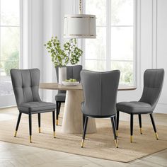 a dining room table with grey chairs and a white rug on the floor in front of it