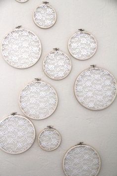 there are many small white embroidery hoops hanging on the wall