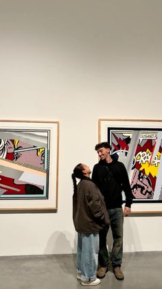 two men standing in front of paintings on display at an art gallery with one man holding the other's head