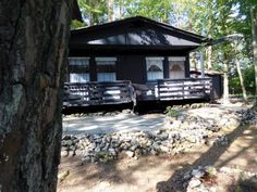 a small cabin in the woods with rocks and trees around it's perimeter,