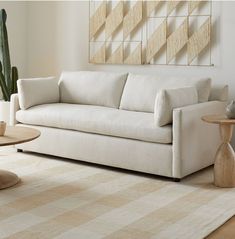 a white couch sitting on top of a rug in a living room next to a table