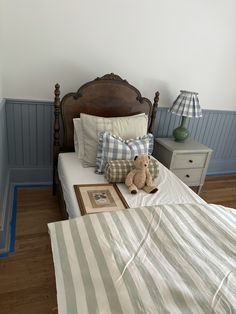 a teddy bear sitting on top of a bed in a room with blue and white walls