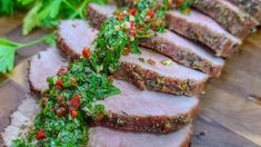 sliced meat with herbs and seasoning sitting on a cutting board