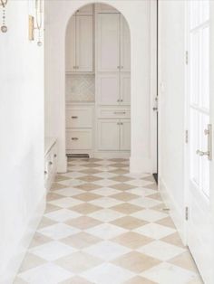 a hallway with white cabinets and checkered flooring on the tile in front of it