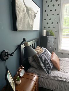 a bedroom with blue walls and a cow painting on the wall above the headboard