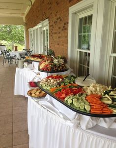 an outdoor buffet with many different types of food on it's long serving trays