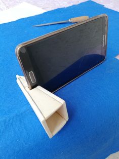 a cell phone sitting on top of a blue blanket next to a piece of wood