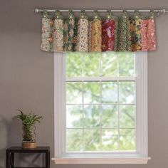 the window is decorated with colorful curtains and potted plants in front of it,