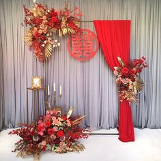 a red and gold wedding set up with flowers, candles and decorations on the stage