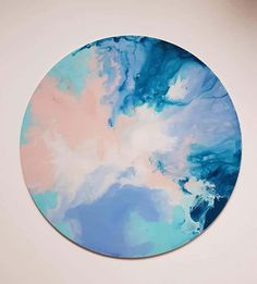 a round painting with blue, pink and white clouds on it