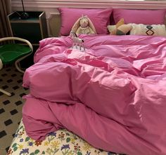 a stuffed animal is sitting on top of a pink comforter in a room with black and white checkered flooring