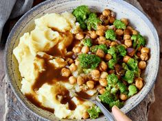 a bowl filled with mashed potatoes and broccoli covered in gravy