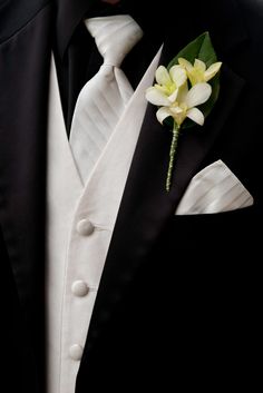 a man in a tuxedo wearing a boutonniere and white flower