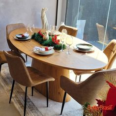 a dining table set for christmas with plates and wine glasses on it, surrounded by holiday decorations